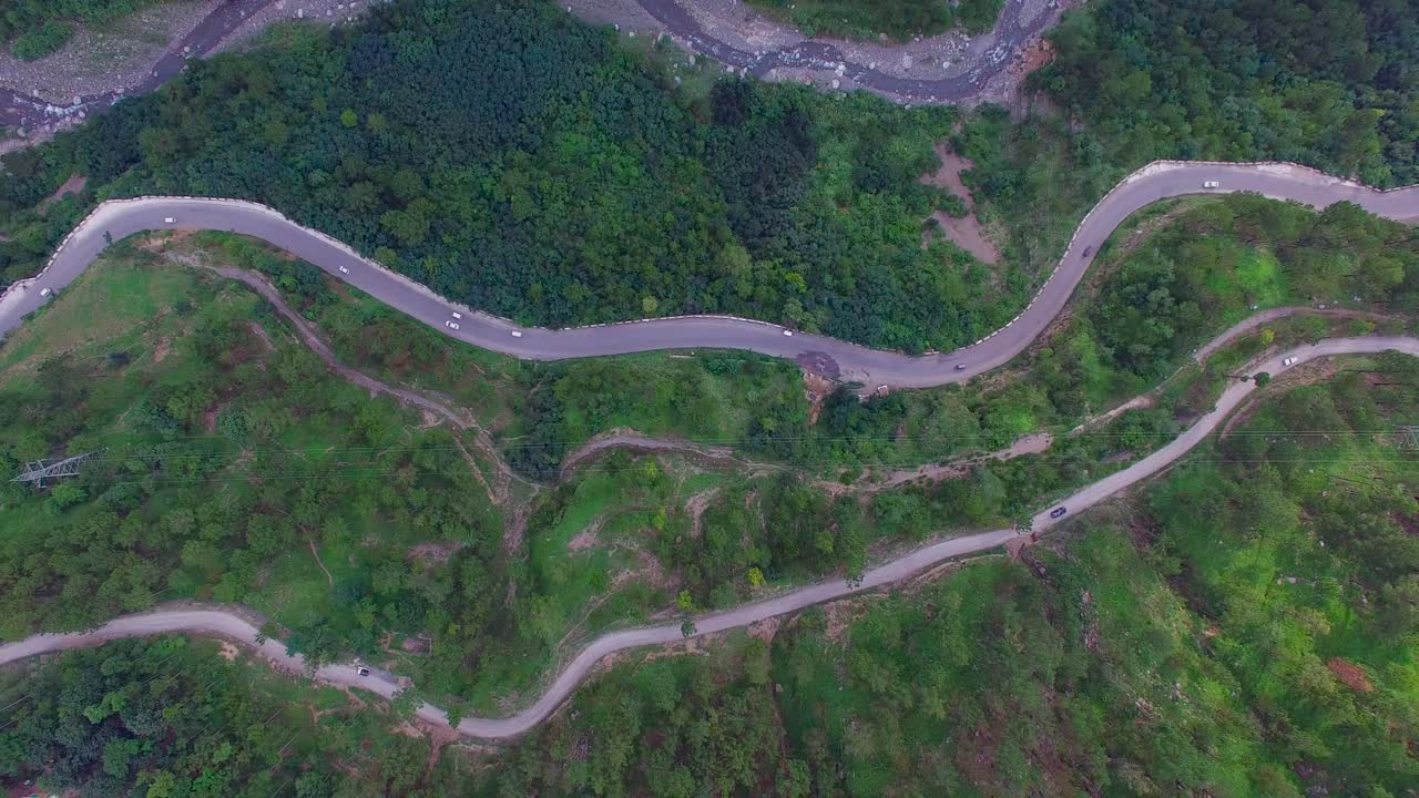 vista superior de la carretera en zigzag, kahmir, india, hay tráfico, grandes bosques y árboles verdes, remolcar la carretera en zigzag y una vista del río desde la altura máxima