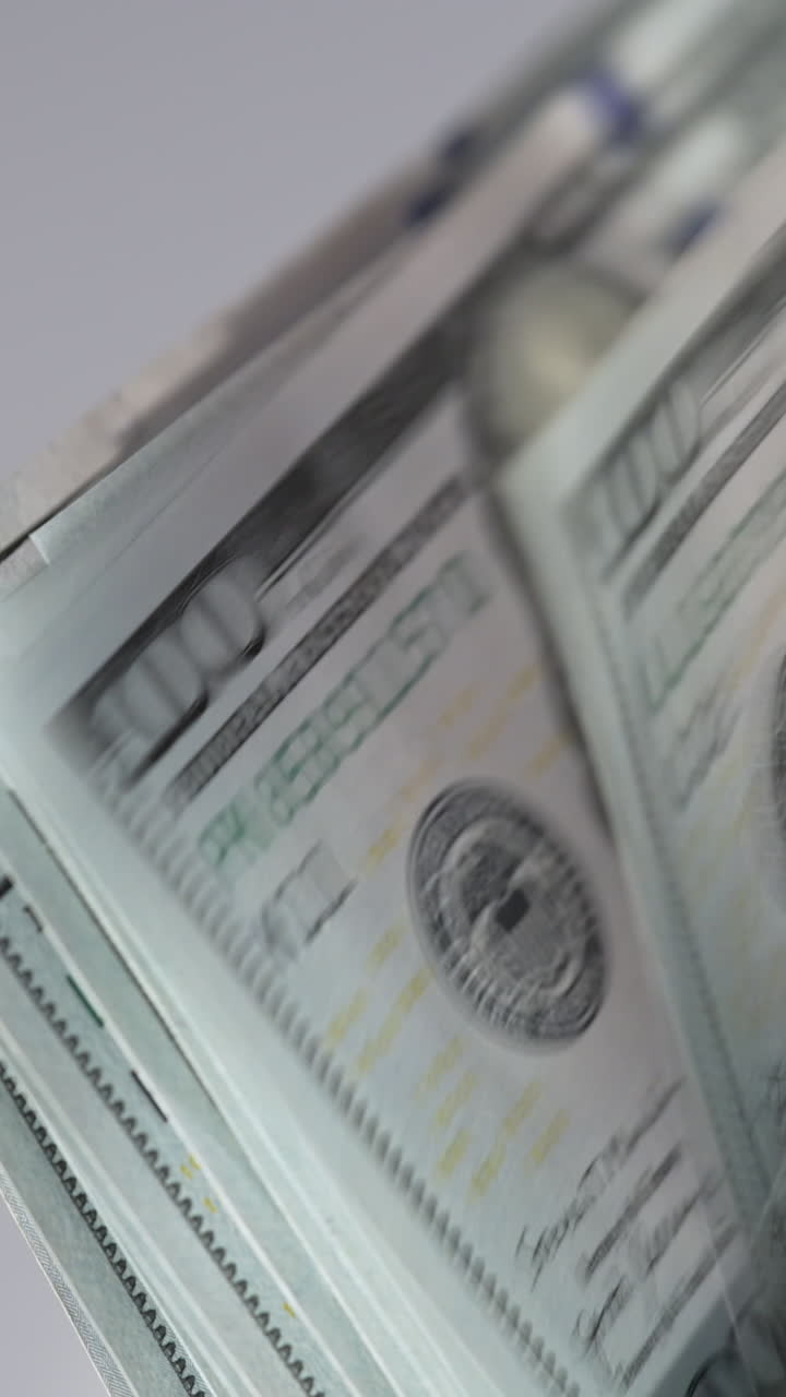 One hundred dollar banknotes falling quickly on the holder of cash machine. US currency counted in the special equipment. Close up. Vertical video