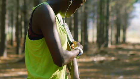 Female-jogger-adjusting-arm-band-in-the-forest-4k