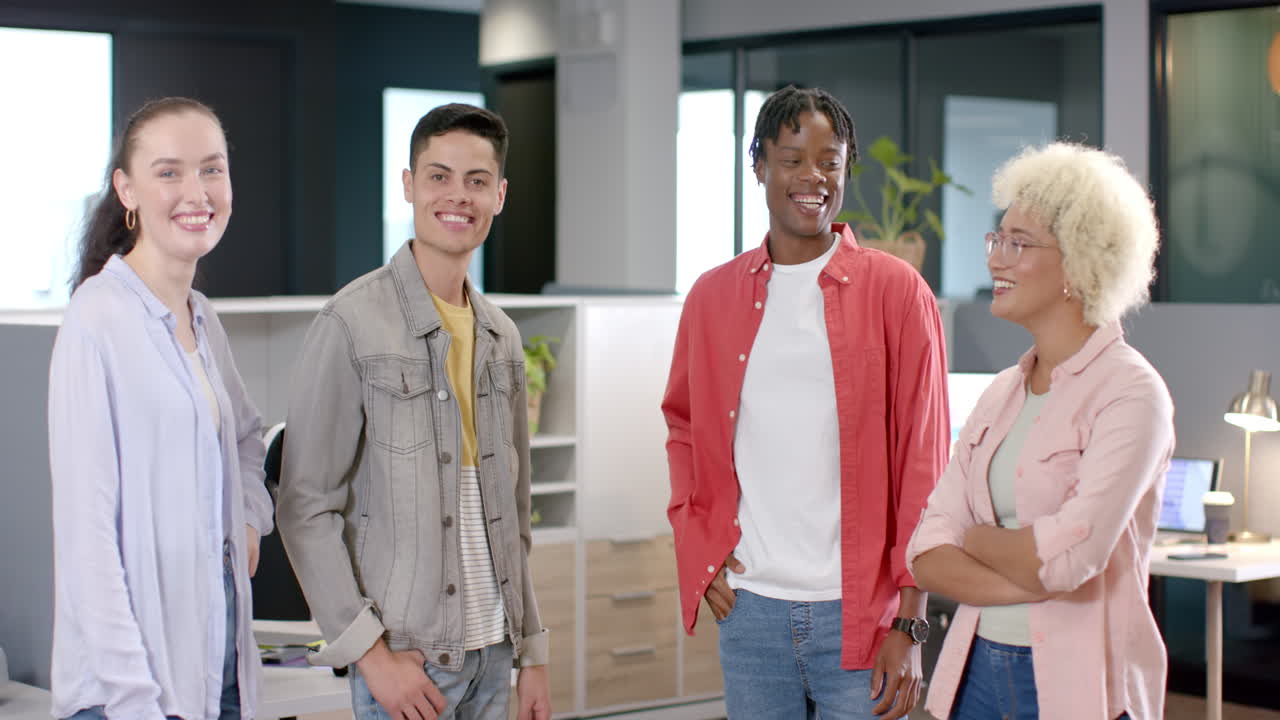 Smiling group of diverse colleagues standing together in modern office workspace