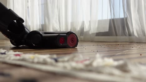 close up of a vacuum cleaner cleaning a wood floor with a rug in the foreground