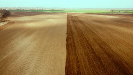 aerial drone shot of farm field, half plowed, half unplowed during cloudy day