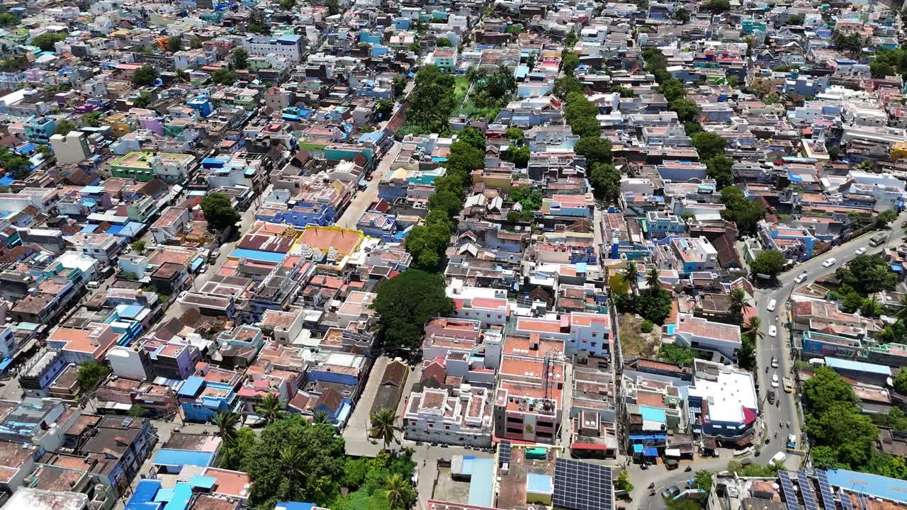 A breathtaking aerial panorama of the Tenkasi district, Tamil Nadu, India, nestled at the base of the Ghats. The scene captures a vibrant townscape with colorful houses surrounded by lush greenery