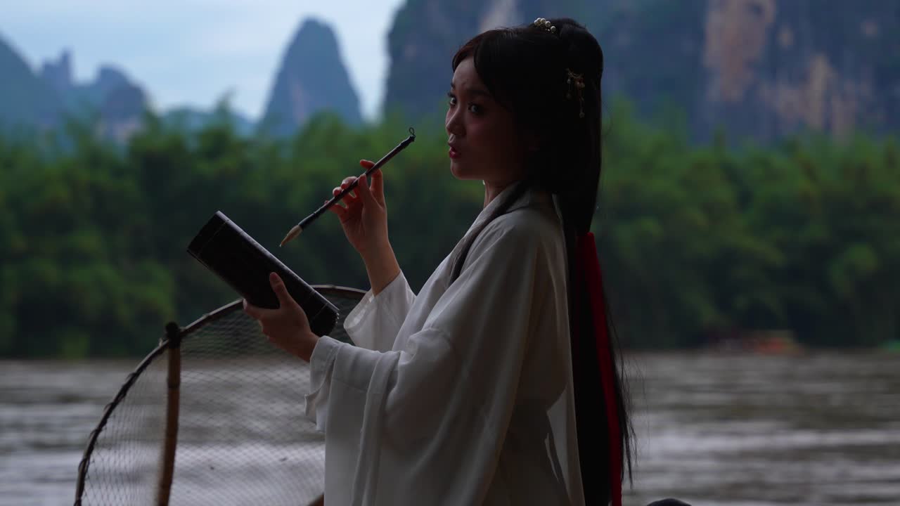 Medium shot of beautiful Hanfu lady with quill in front of scenic landscape in Xingping, China