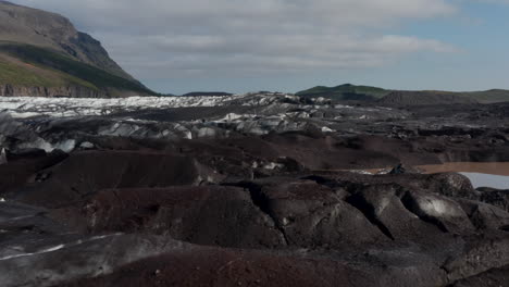 Erstaunliche-Drohnenansicht-Der-Breidamerkurjokull-Gletscherzunge-Und-Der-Vulkanberge-In-Der-Umgebung.-Vogelperspektive-Von-Vulkanischen-Felsformationen-Und-Gefrorenem-Gletschereis-Im-Vatnajokull-Nationalpark