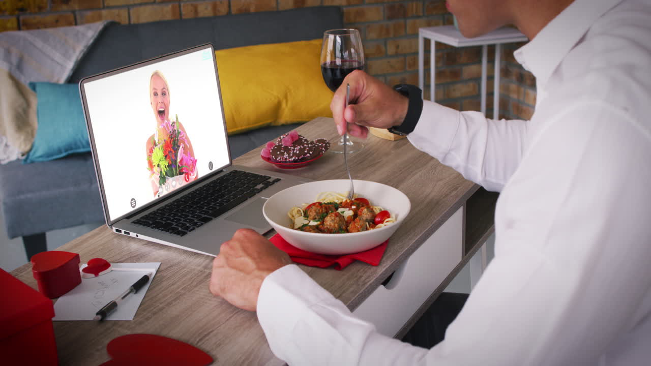 una pareja celebra el día de san valentín en línea con comida y flores durante el bloqueo.