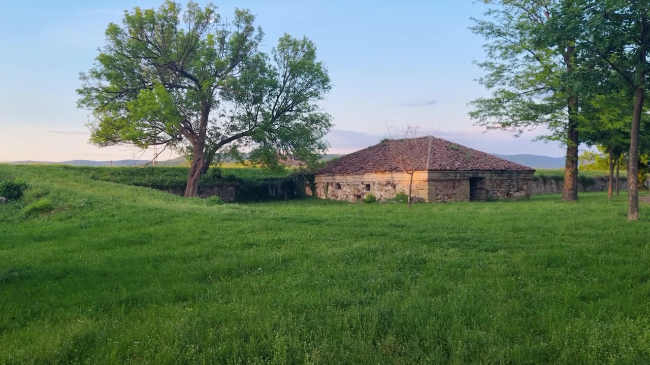 Pemandangan sore Gudang Mesiu Ottoman (Barutane) di dalam Benteng Niš, Serbia, bermandikan cahaya matahari hangat dan dikelilingi rumput hijau subur, suasana damai di tengara bersejarah ini