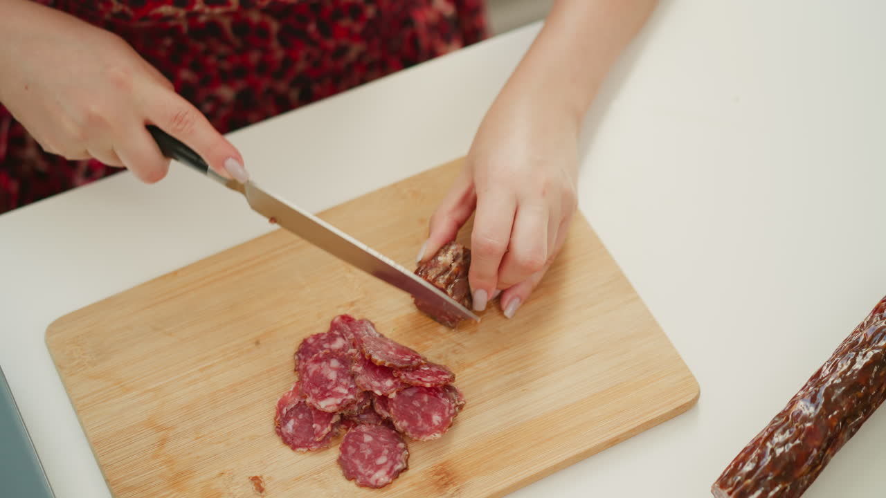 Woman cutting sausage on a wooden cutting board