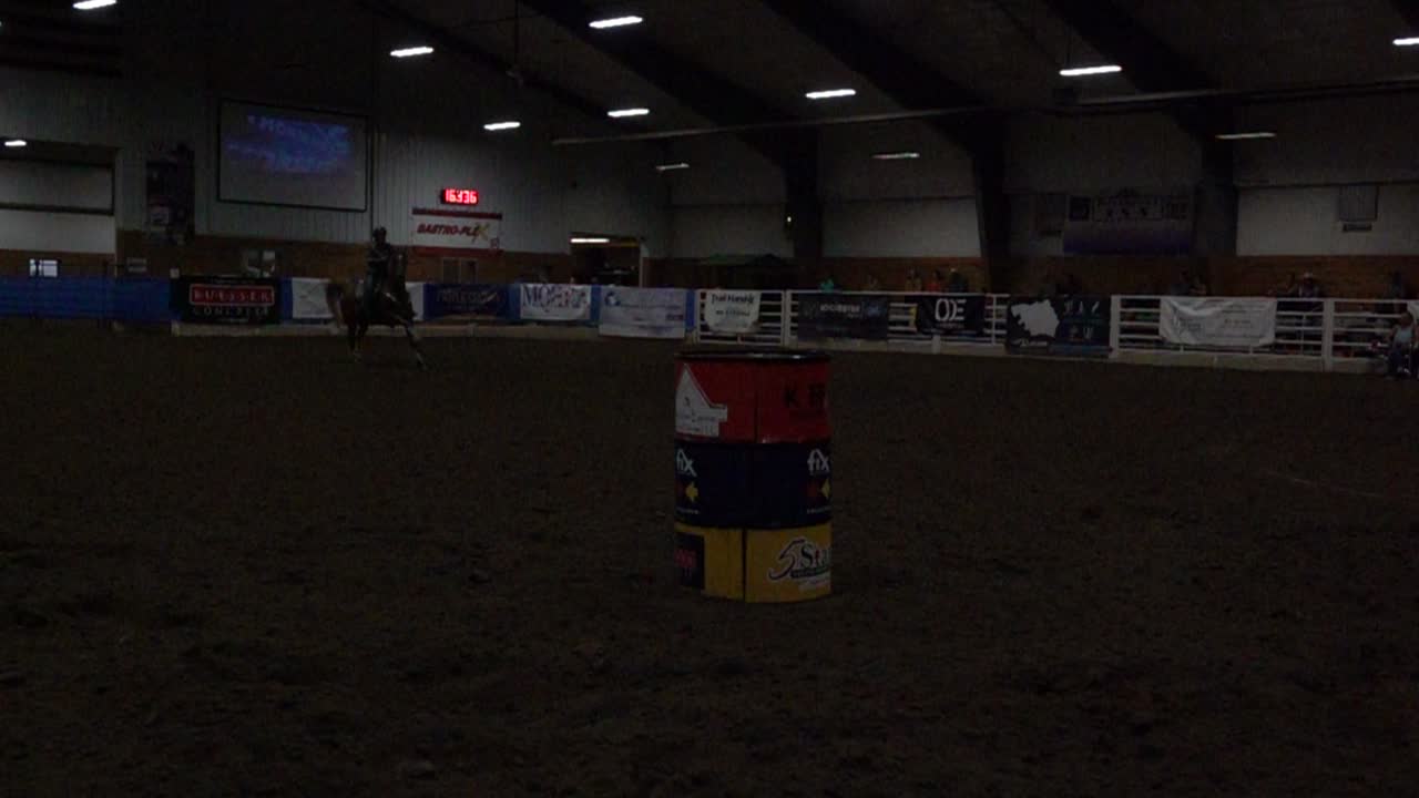 Gara di Barrel Racing con cavallo e cavaliere in arena al coperto