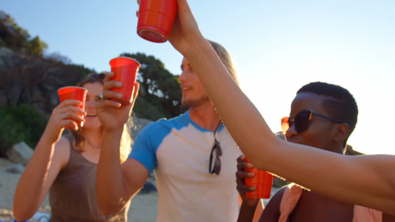 grupo de amigos brindando copas de cerveza en la playa 4k
