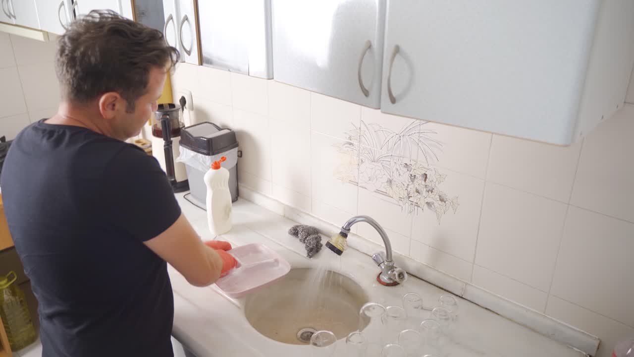 hombre lavando los platos en la cocina.