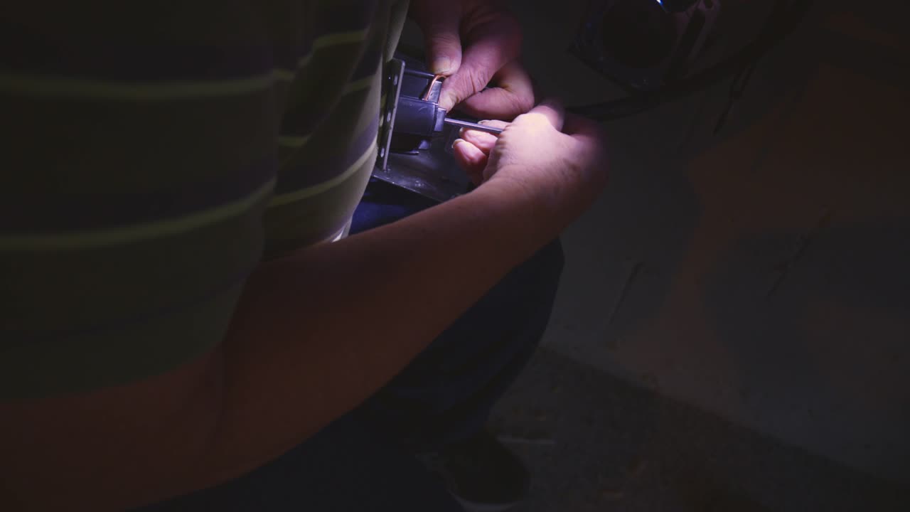 Lavoro di team: delle mani che collaborano illuminano una scatola di derivazione per veicoli elettrici mentre un'altra persona stringe i cavi elettrici sovradimensionati a un caricabatterie per veicoli elettrici a casa.