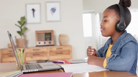 Fröhliches,-Unverändertes-Afroamerikanisches-Mädchen,-Das-Laptop-Und-Kopfhörer-Für-Den-Online-Unterricht-Benutzt,-In-Zeitlupe