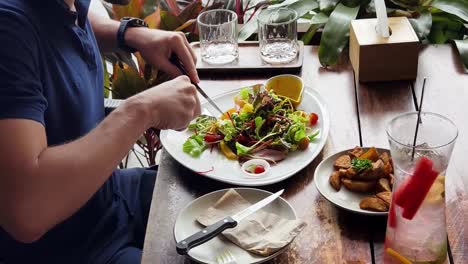hombre comiendo ensalada en un restaurante