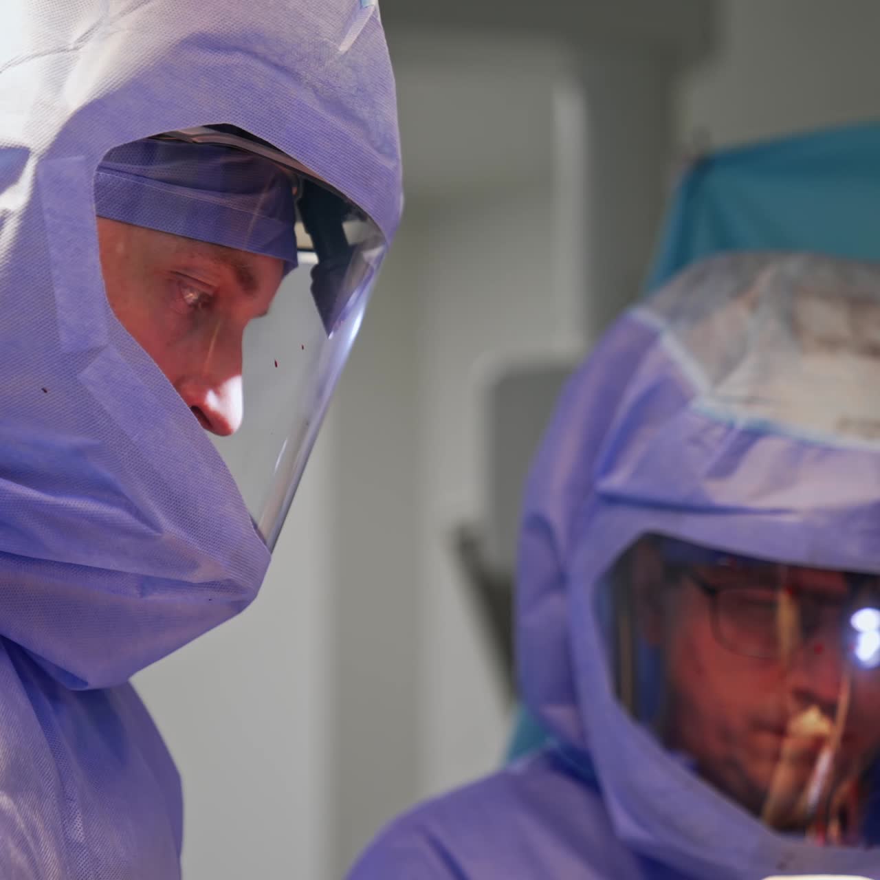 Medici concentrati che guardano il paziente sul tavolo operatorio. Primi piani di chirurghi che indossano le tute protettive
