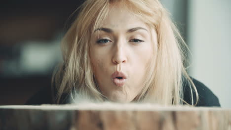 female carpenter blowing off sawdust on tree stump