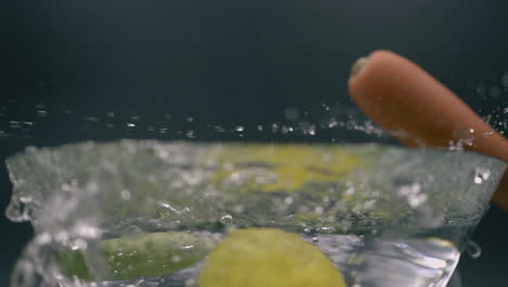 fresh vegetables splashes on the transparent glass bowl with water.- slow motion