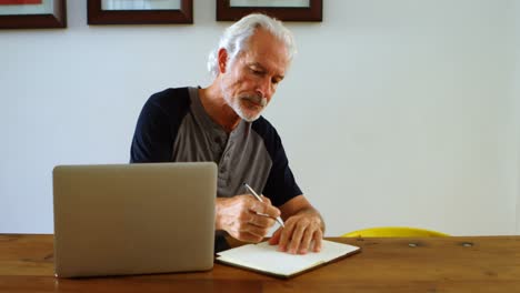 Senior-man-writing-on-notepad-on-table-4k