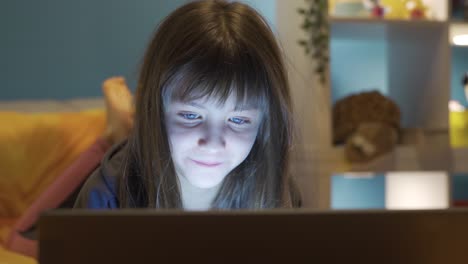 Little-girl-looking-at-laptop-in-night-room.-Happy-little-girl.