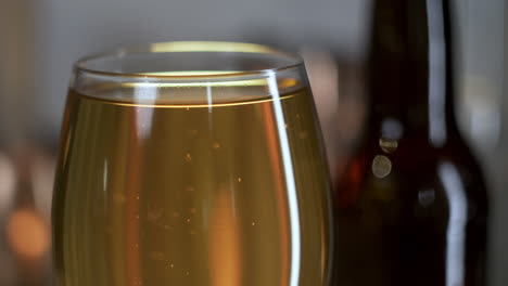 close up on beer bubbles with bottle in background