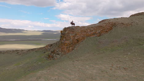 Blick-Auf-Einen-Adlerjäger,-Der-Im-Westen-Der-Mongolei-Auf-Dem-Pferd-Reitet---Drohnenaufnahme