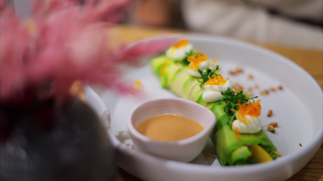 Close up of an avocado roll with sauce on a white plate at a restaurant