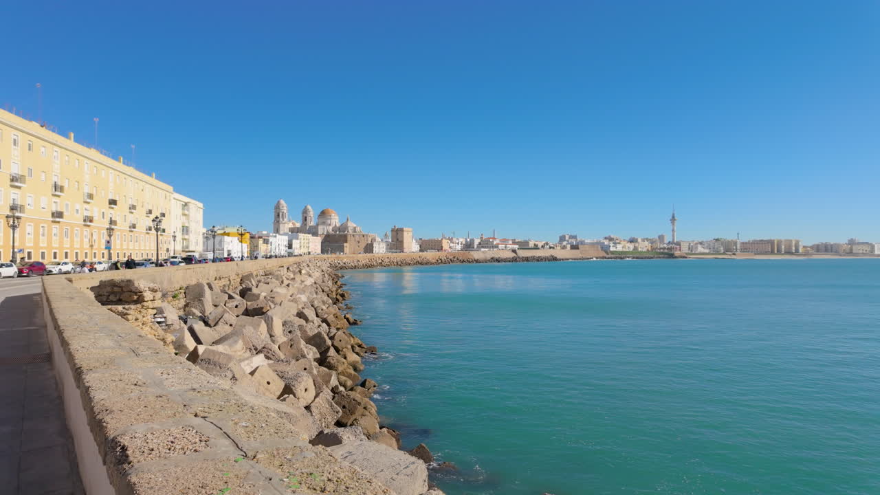 A seaside promenade with a long stretch of buildings alongside the coastline, reflecting Cadiz's coastal charm and maritime history