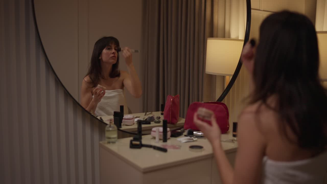 mujer aplicando maquillaje frente a un espejo