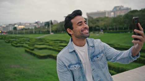 un chico alegre llamando por teléfono inteligente en el parque verde de cerca. hombre sonriente