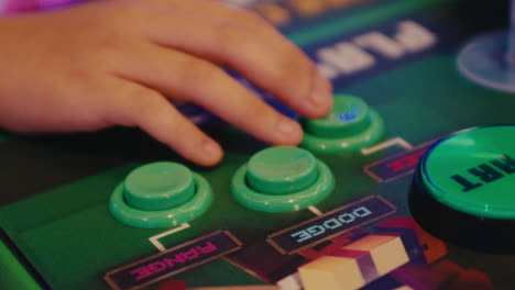 young kind hand close up while playing with arcade video games pressing green buttons controllers