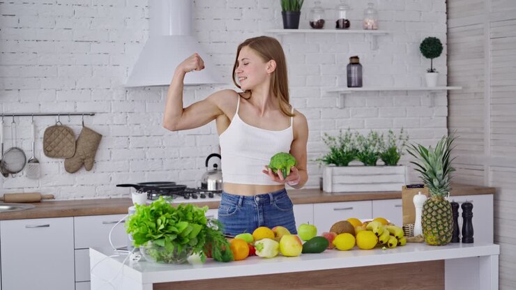 Donna sorridente e in forma in cucina. Giovane donna con corpo muscoloso in piedi in cucina.