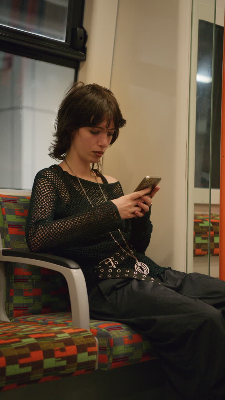 video vertical de una mujer de estilo alternativo usando un teléfono móvil sentada en el metro de londres en tiempo real