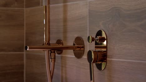 Slow-revealing-shot-of-the-golden-shower-faucet-and-controls-in-a-modern-bathroom