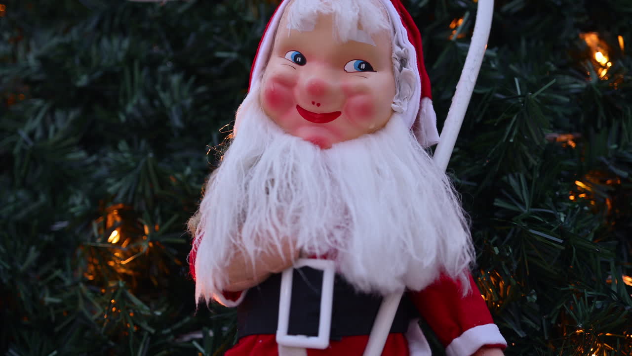 Festive Santa Claus decoration displayed outdoors, framed by Christmas tree branches and warm holiday lights