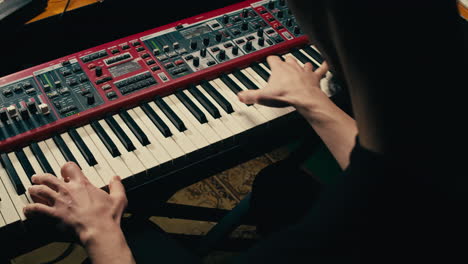 close up of keyboard player hands playing rock music with keyboard at the concert in studio, rehearsal room, macro play on synthesizer.