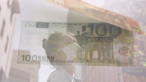 Digital-composite-video-of-Euro-bills-moving-against-woman-wearing-face-mask-in-background