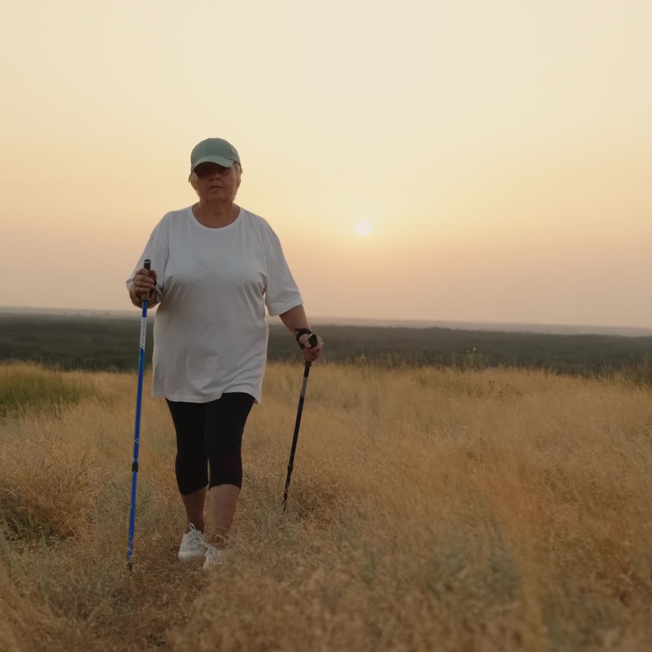 En eldre kvinne med nordic walking-staver går fremover gjennom et naturskjønt sted 1