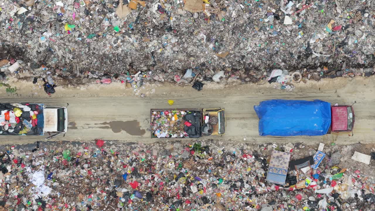 Vista aerea dall'alto di camion della spazzatura che si muovono attraverso una grande discarica