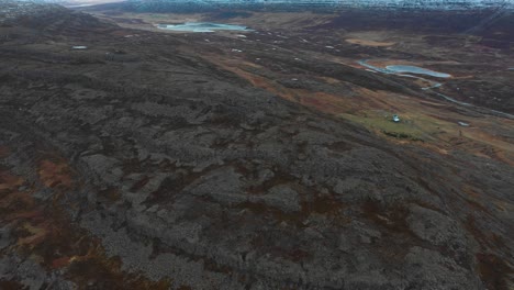 Rotating-aerial-view-of-a-highway-running-between-the-vast-mountainous-terrain-and-endless-blue-sea-showing-blissful-nature