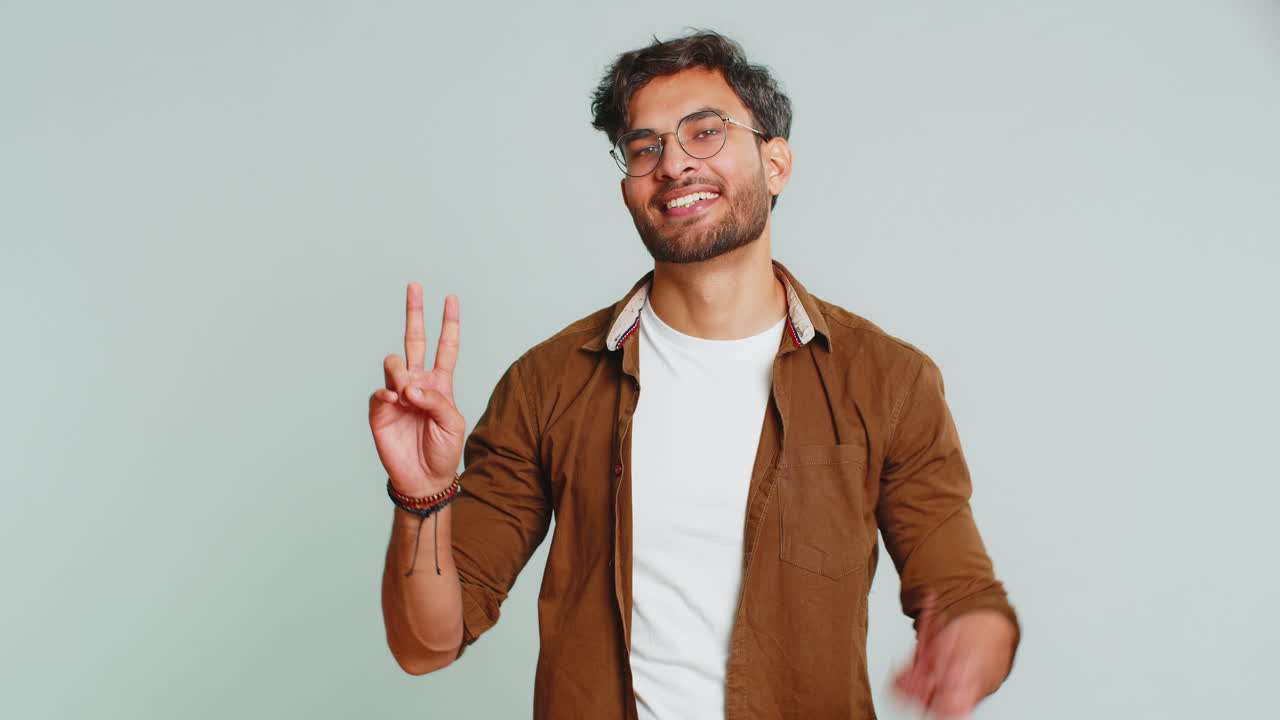 un joven indio feliz y sonriente mostrando el signo de la victoria, esperando el éxito y la victoria, haciendo un gesto de paz