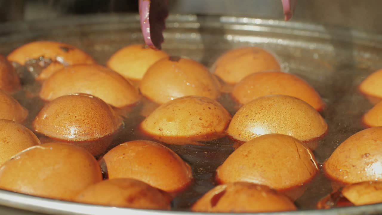 Chinese century eggs or tea egg in boiling water close-up. Chinese egg-based culinary dish made by preserving duck, chicken, or quail eggs in a mixture of clay, ash, salt, quicklime, and rice hulls for several weeks to several months.Korean mayak eggs or mayak gyeran are boiled eggs marinated in a f