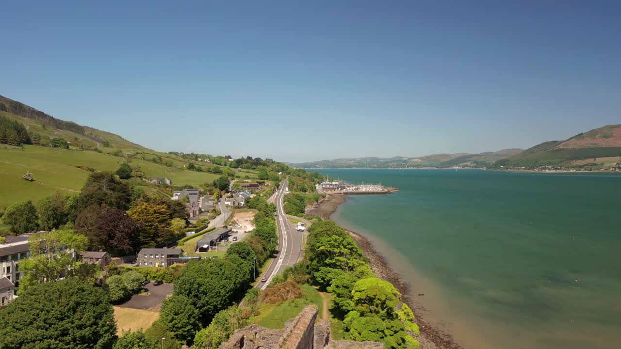 Wide, rising aerial video of Carlingford Castle and Carlingford Lough in Carlingford, County Louth, Ireland on a bright and sunny day. Filmed in 4K, 60FPS and with Rec709 color.