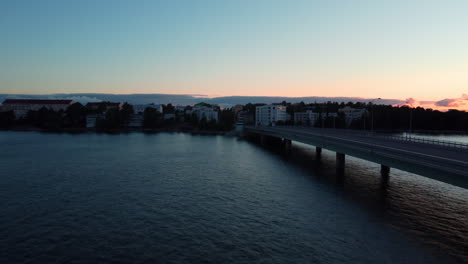 Aerial-view-rising-over-the-Lauttasaarensilta-bridge-towards-Lauttasaari-city,-dusk-in-Helsinki,-Finland