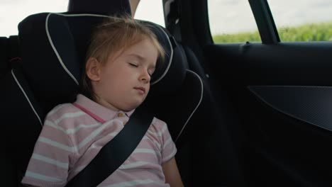 caucasian little girl sleeping while riding in car.