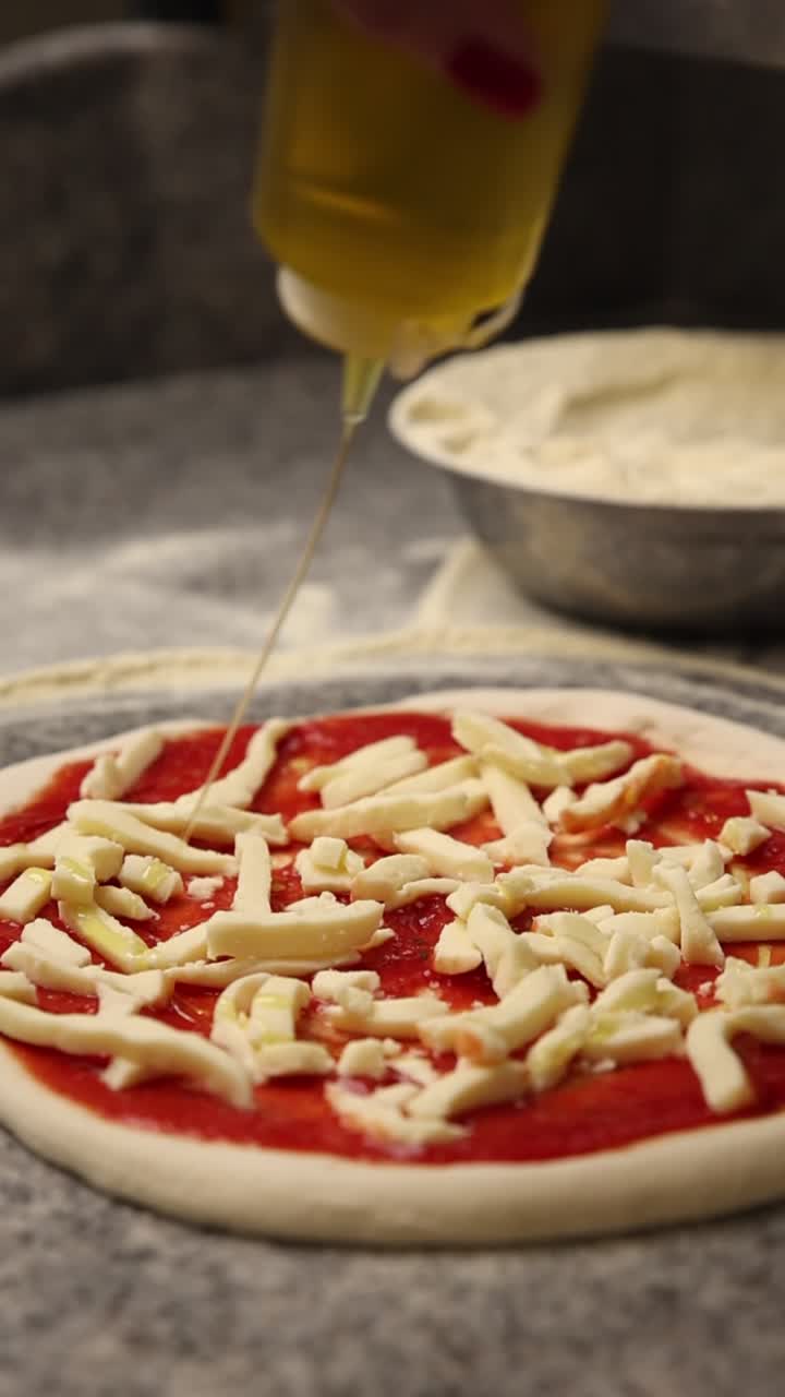 Un filo d'olio d'oliva su una pizza cruda con mozzarella e salsa di pomodoro