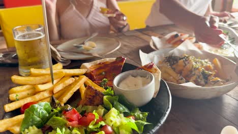casual dining scene with beer, fries, salad, and pizza at a beach club in phuket, thailand. warm lighting and relaxed atmosphere