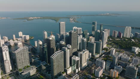 Aerial-footage-of-luxury-apartment-building-complex-along-sea-coast.-Calm-water-surface-and-island-in-background.-Miami,-USA