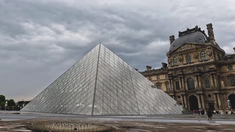 turistas que visitan la famosa pirámide de vidrio del louvre