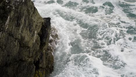 breaking foamy waves at the rocky cliffs near newquay harbour, cornwall, england