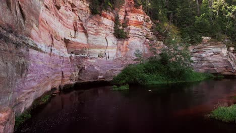 this close aerial perspective highlights the unique texture and scale of taevaskoja sandstone cliffs with a calm river and dense forest creating a captivating estonian outdoor scene